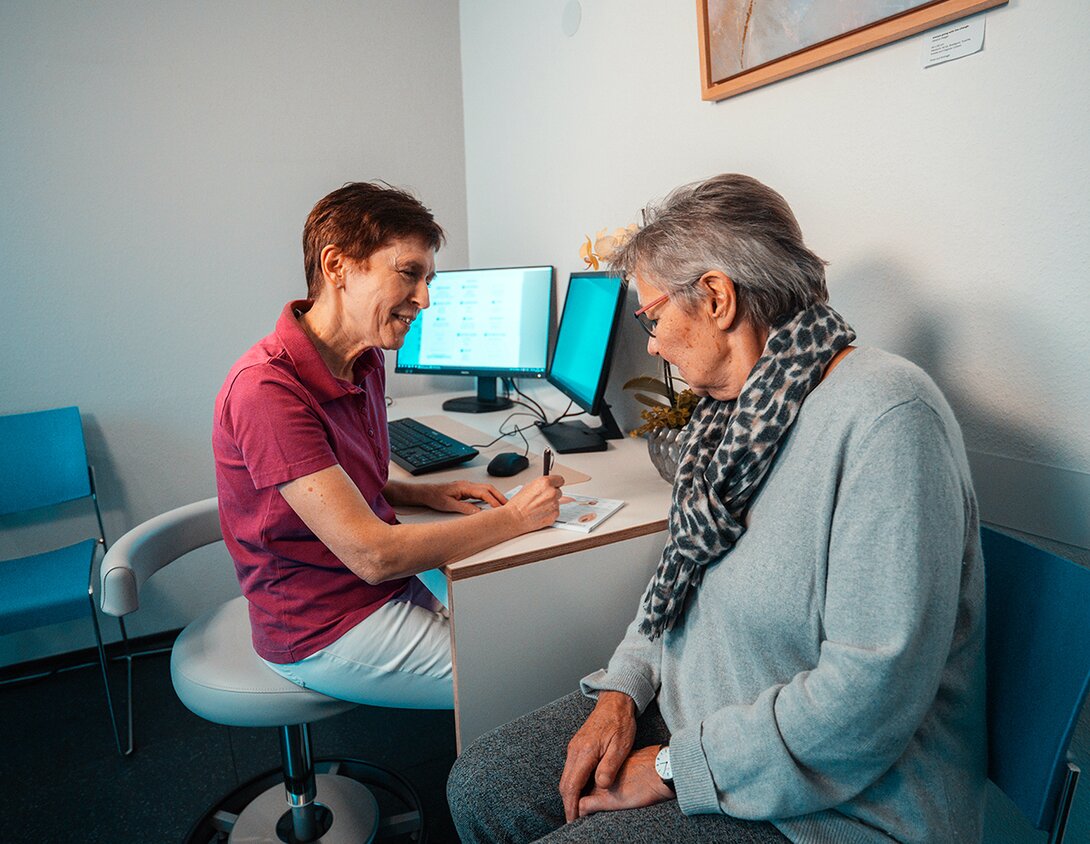 Ärztin spricht beruhigend mit Patientin im Untersuchungsraum